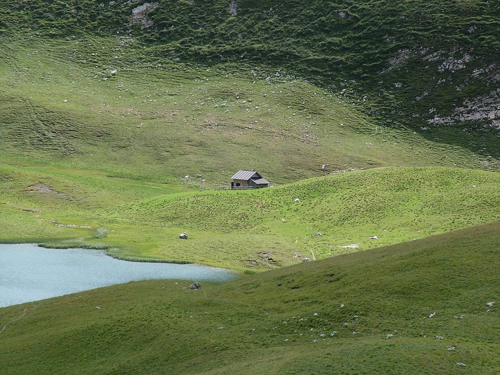 Rechts hinter dem See steht eine Hütte.