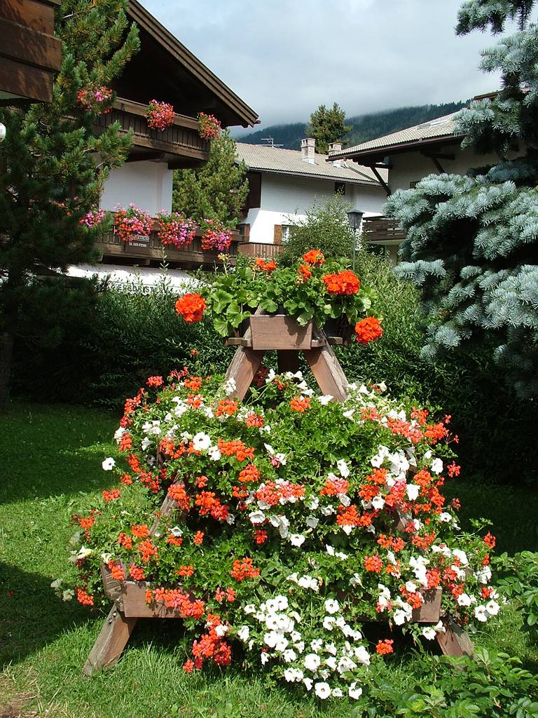 In einem Garten steht dieser wunderschöne Blumenständer.