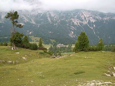 Links von uns, unten im Tal an der Pl&auml;tzwiese, liegen nebeneinander ein Hotel und eine H&uuml;tte.