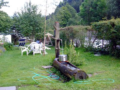 Im Vorgarten des Hauses gibt es einen Holzstamm als Quelle, hier mit Edelstahl–Einsatz.