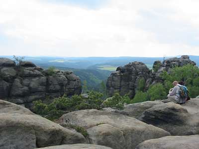 Zwischen den Felsen hindurch kann man den weiten Bogen des Elb-Tales sehen.