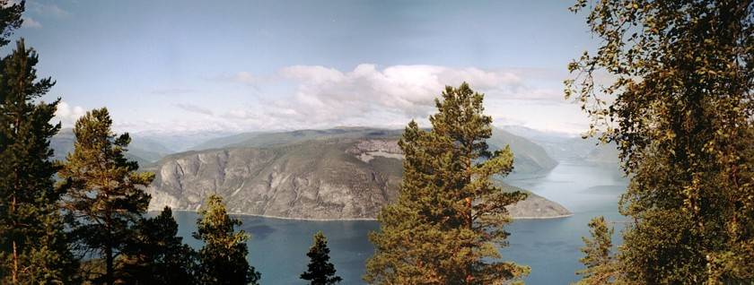 Wir sind um die Spitze herumgewandert und schauen jetzt in Richtung Norden, über den Fjord zum gegenüberliegenden Ufer bei Kaupanger. Ganz fern ist der Jostedalsbreen zu erahnen und rechts kommt jetzt auch der Lustrafjorden ins Bild.